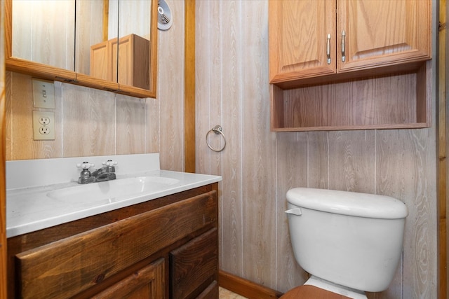 bathroom featuring wooden walls, vanity, and toilet