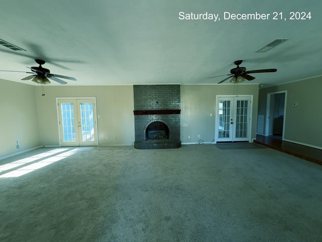 unfurnished living room with french doors, carpet floors, a brick fireplace, and ceiling fan