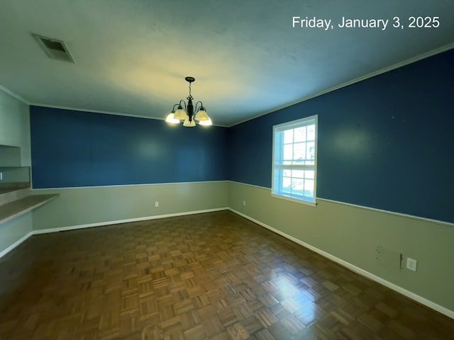 spare room with dark parquet flooring, ornamental molding, and an inviting chandelier