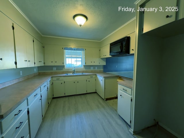 kitchen with a textured ceiling, light hardwood / wood-style floors, white cabinets, and sink