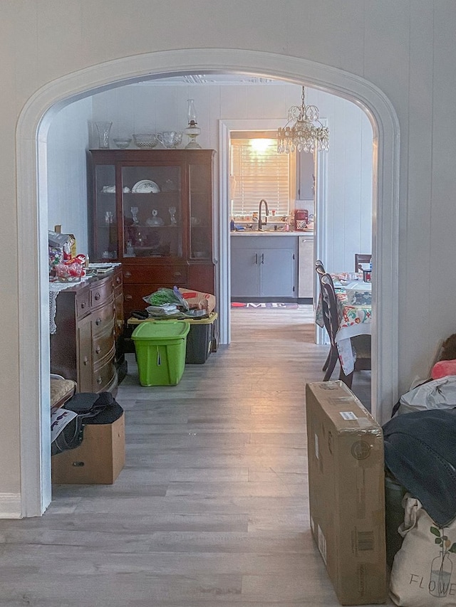 hall with light hardwood / wood-style floors, sink, and an inviting chandelier