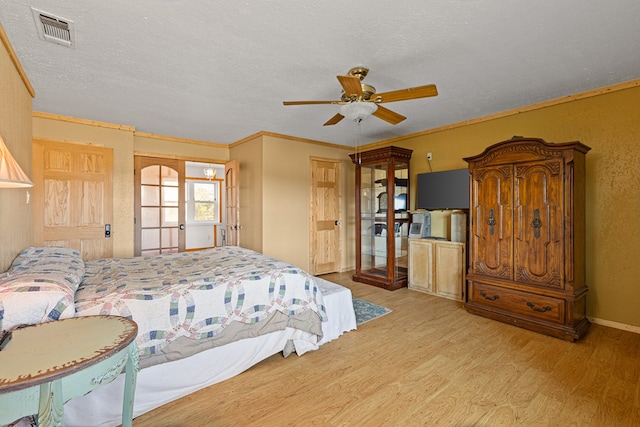 bedroom with ceiling fan, crown molding, light hardwood / wood-style flooring, and a textured ceiling