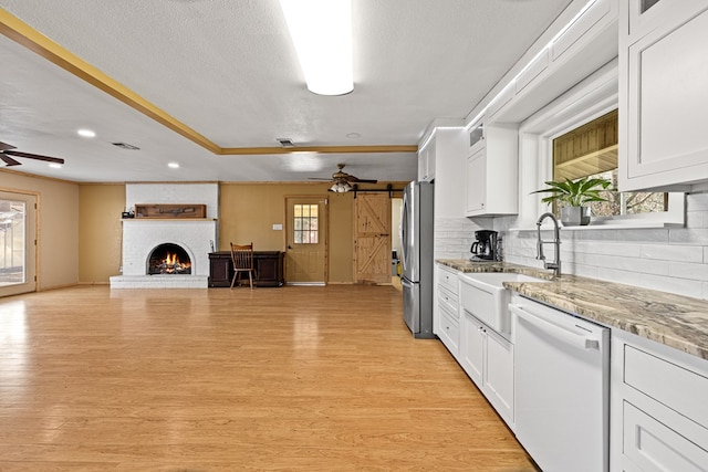 kitchen with white cabinetry, stainless steel fridge, a barn door, and dishwasher