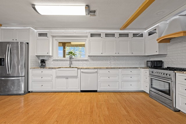 kitchen featuring stainless steel appliances, tasteful backsplash, white cabinets, and light wood-type flooring