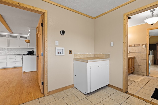 laundry area featuring light tile patterned floors, crown molding, tile walls, hookup for a washing machine, and a textured ceiling