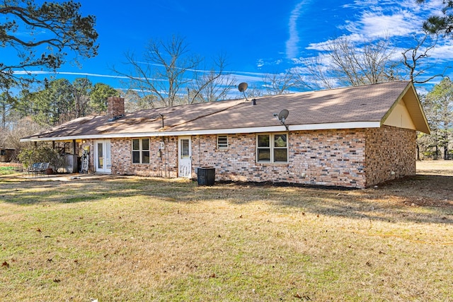 rear view of property with central AC unit and a yard