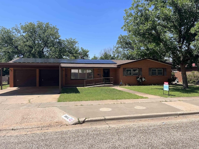 ranch-style house featuring a front yard, solar panels, and a carport