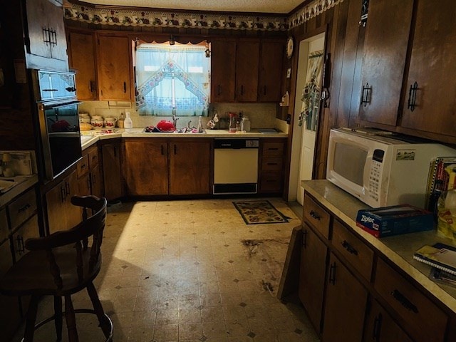 kitchen with dark brown cabinets, sink, a textured ceiling, and white appliances