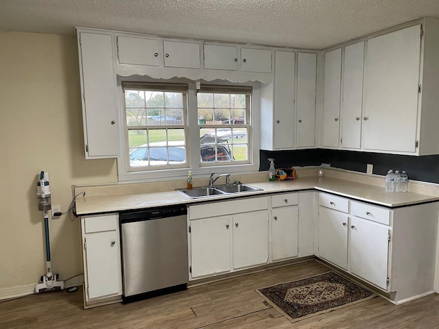 kitchen featuring dishwasher, white cabinets, hardwood / wood-style flooring, and sink