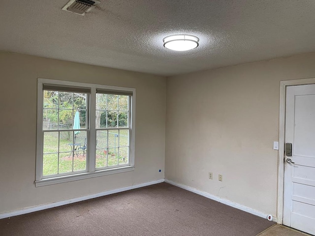 carpeted empty room with a textured ceiling