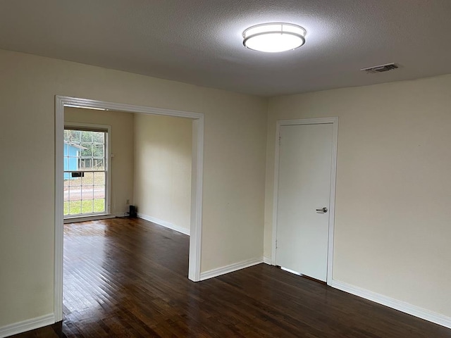 unfurnished room featuring dark hardwood / wood-style flooring and a textured ceiling