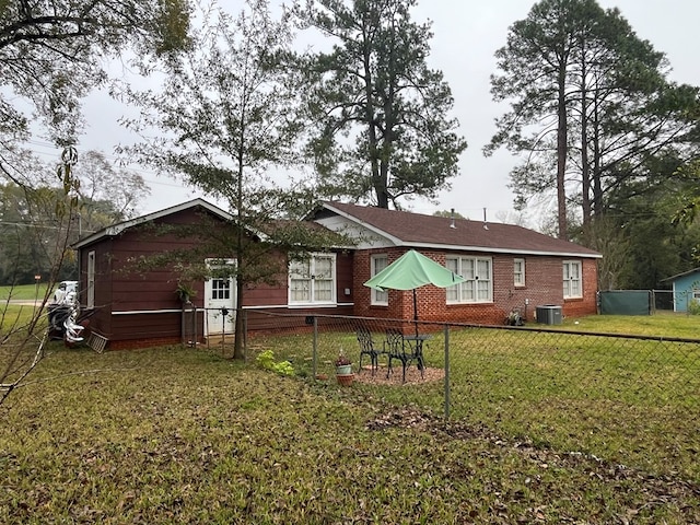 rear view of property featuring central AC unit and a yard