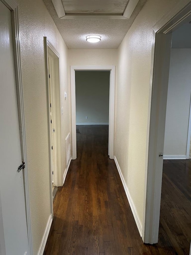 hall featuring dark hardwood / wood-style floors and a textured ceiling