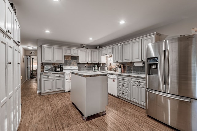 kitchen with a center island, light wood-type flooring, appliances with stainless steel finishes, tasteful backsplash, and white cabinetry