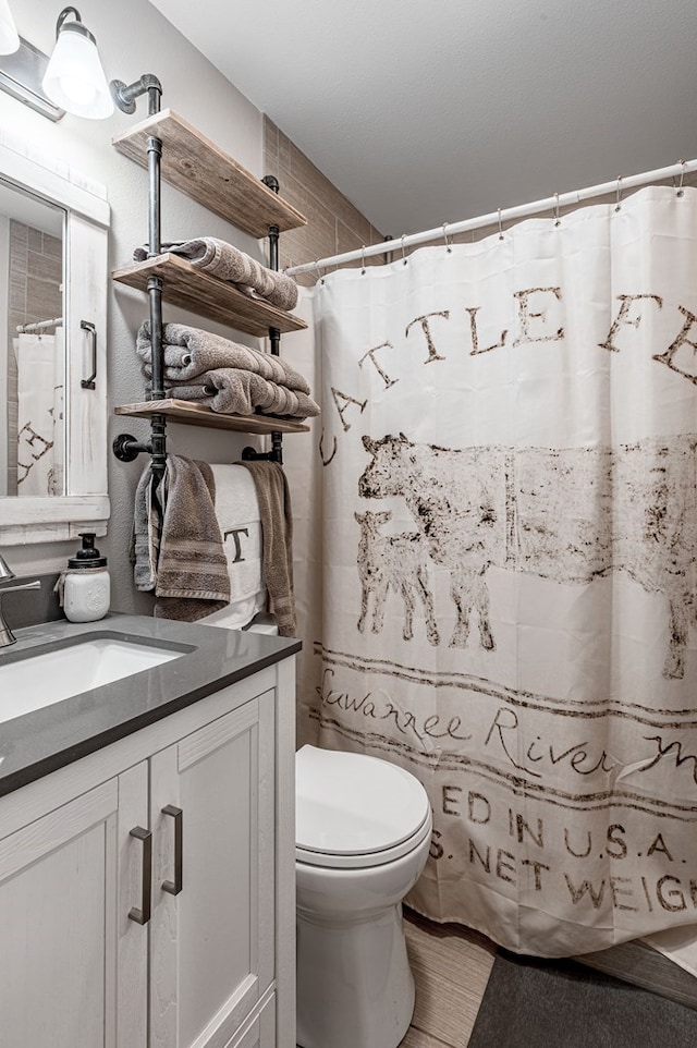 bathroom with a shower with shower curtain, vanity, and toilet