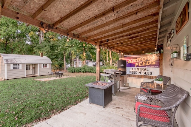 view of patio featuring a wooden deck, an outbuilding, and an outdoor fire pit