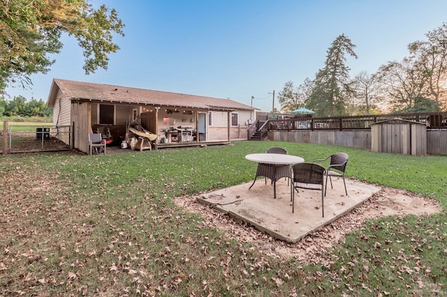 view of yard featuring a patio, a deck, and a storage unit