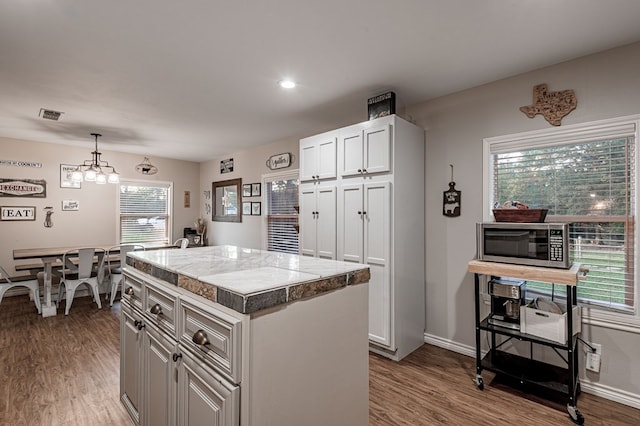 kitchen with hanging light fixtures, a center island, white cabinets, and wood-type flooring