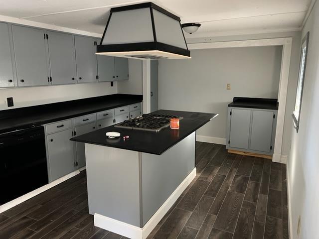 kitchen featuring dishwasher, dark hardwood / wood-style flooring, premium range hood, stainless steel gas stovetop, and a kitchen island