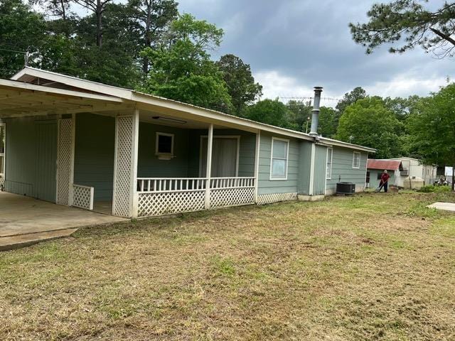 view of property exterior with covered porch, central AC unit, a carport, and a lawn