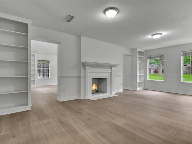 107 Bending Oak Dr, Lufkin, TX 75904 - unfurnished living room featuring built in shelves, wood finished floors, and a lit fireplace