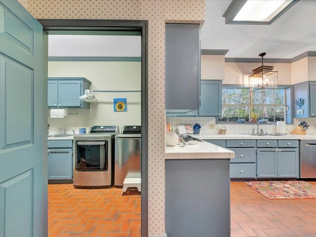 2211 Copeland St, Lufkin, TX 75904 - kitchen featuring washer and clothes dryer, a sink, stainless steel dishwasher, brick floor, and wallpapered walls
