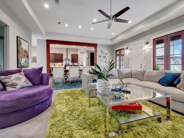 living room featuring ceiling fan, a tray ceiling, and french doors