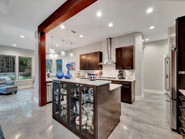 kitchen featuring decorative light fixtures, wall chimney range hood, a kitchen island, stainless steel appliances, and dark brown cabinets