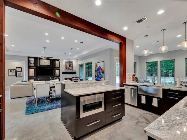 kitchen with a spacious island, dishwasher, pendant lighting, light stone counters, and sink