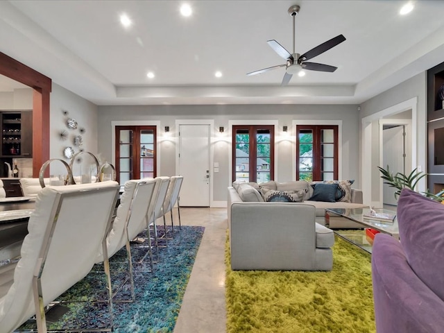 living room with ceiling fan, a raised ceiling, and french doors