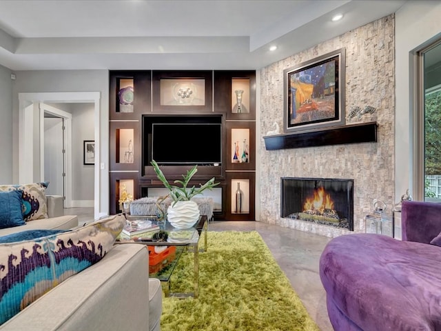 living room featuring a stone fireplace and concrete flooring