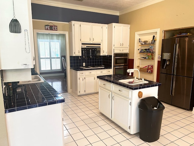 kitchen with white cabinets, appliances with stainless steel finishes, light tile patterned floors, and tile counters