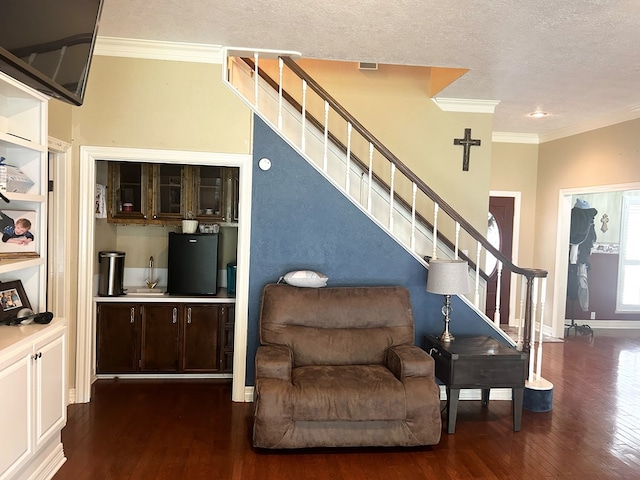 interior space featuring a textured ceiling, wood-type flooring, and ornamental molding