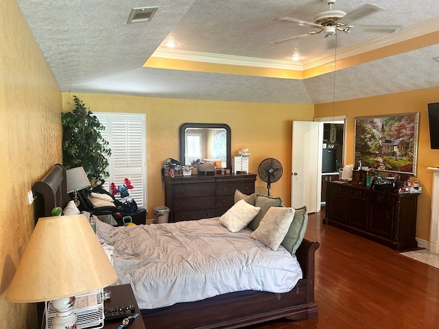 bedroom with a textured ceiling, a tray ceiling, ceiling fan, crown molding, and dark wood-type flooring