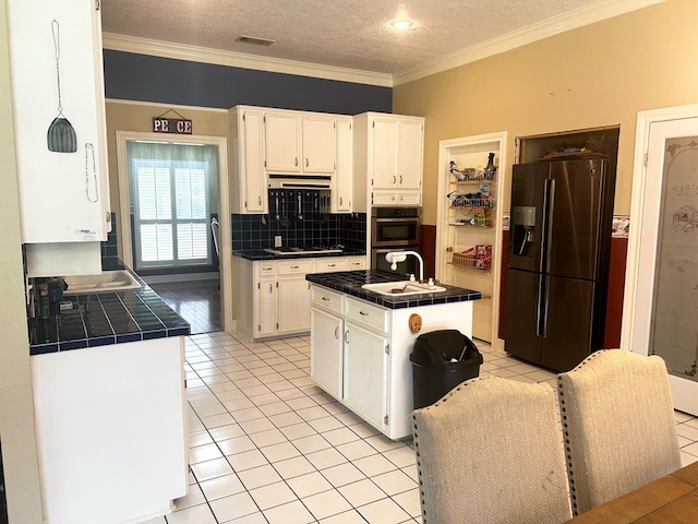 kitchen featuring stainless steel appliances, sink, tile countertops, a center island, and white cabinetry