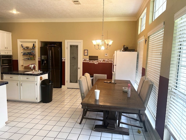 tiled dining room with a notable chandelier, sink, a textured ceiling, and crown molding