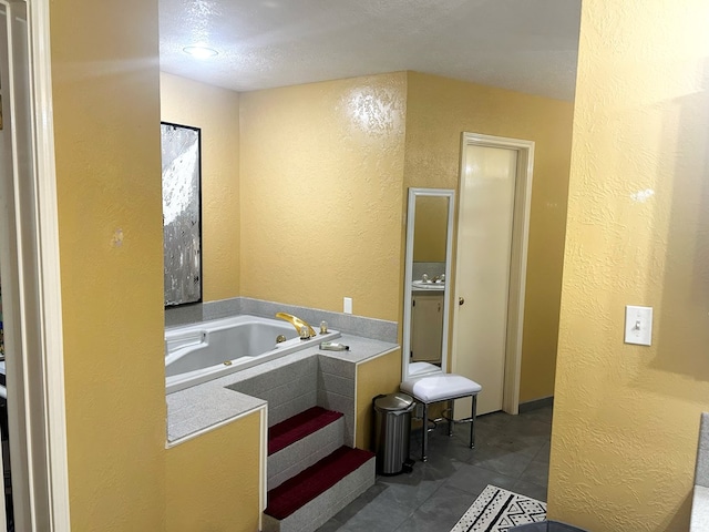 bathroom with tile patterned floors, a bath, and a textured ceiling