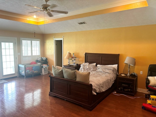 bedroom with dark hardwood / wood-style flooring, ornamental molding, a textured ceiling, a tray ceiling, and ceiling fan