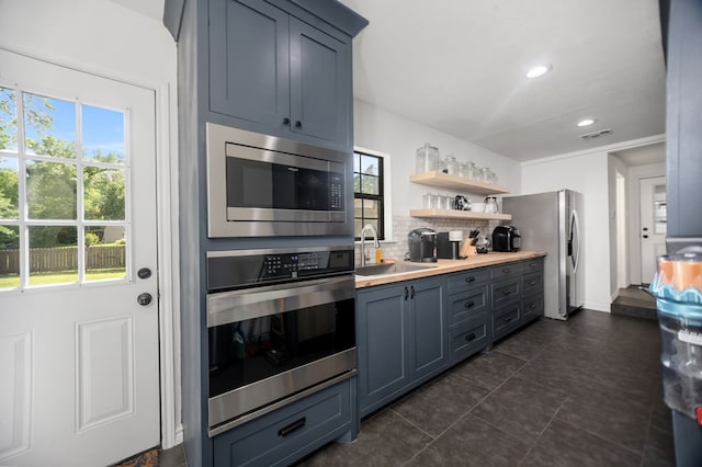 kitchen with appliances with stainless steel finishes, a healthy amount of sunlight, a sink, and tasteful backsplash