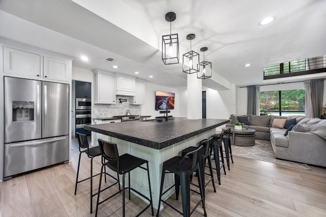 kitchen featuring dark countertops, a breakfast bar, a sink, stainless steel appliances, and open floor plan