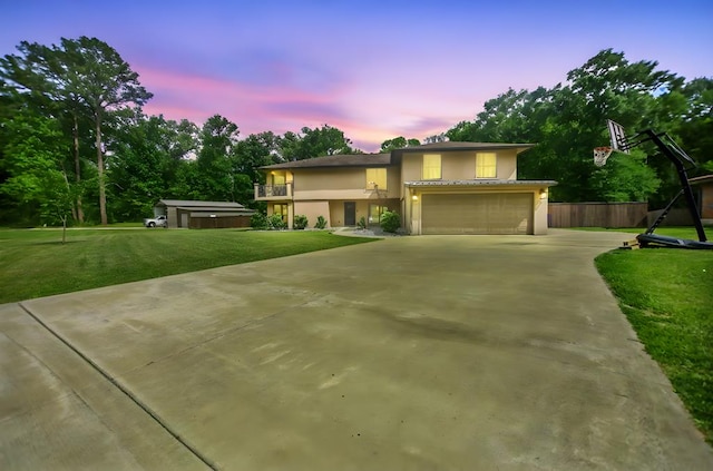 view of front facade featuring a front lawn, fence, a balcony, stucco siding, and driveway