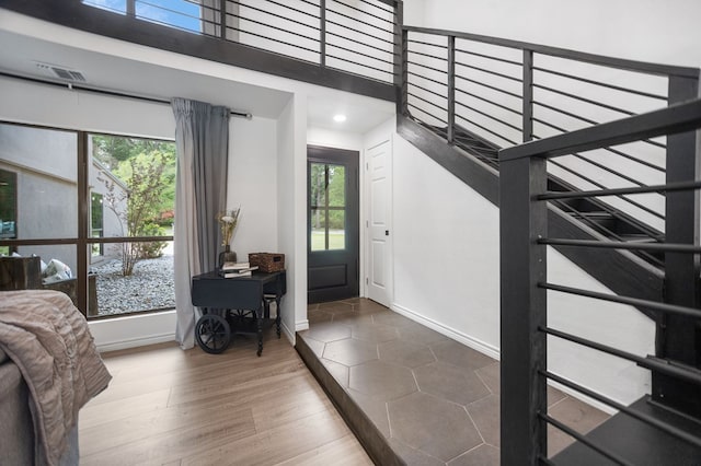foyer with a high ceiling, recessed lighting, baseboards, wood finished floors, and visible vents