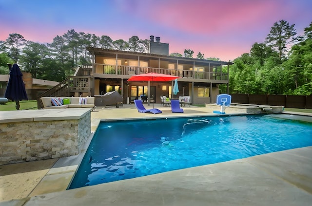 pool at dusk with a patio, an outdoor hangout area, stairs, and a fenced in pool