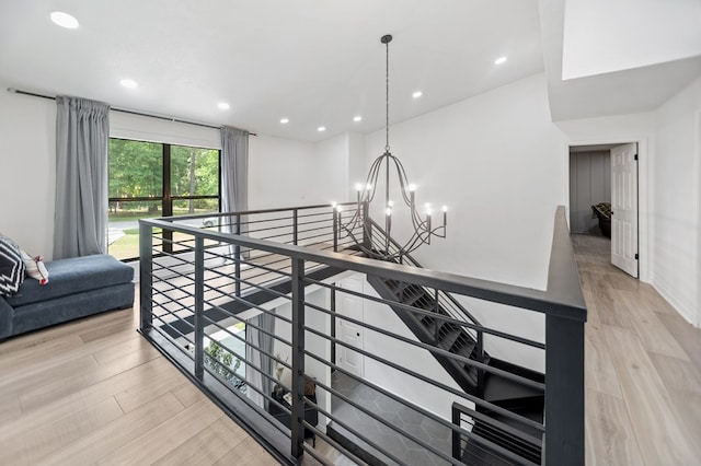 hallway featuring wood finished floors, baseboards, recessed lighting, a notable chandelier, and an upstairs landing