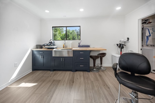 office area featuring washer / clothes dryer, ornamental molding, a sink, and light wood-style flooring