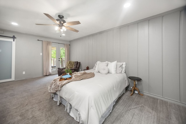 carpeted bedroom with a barn door, access to exterior, french doors, a ceiling fan, and baseboards