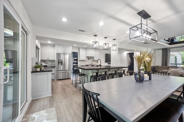 dining space with visible vents, recessed lighting, light wood finished floors, and a chandelier