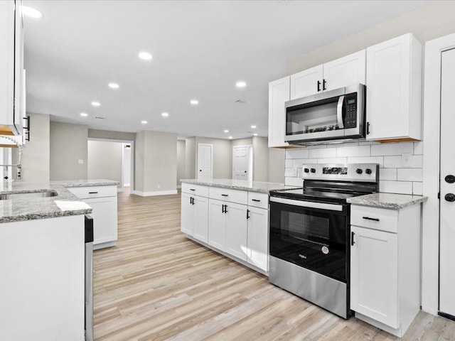 kitchen with white cabinets, light wood-type flooring, and stainless steel appliances