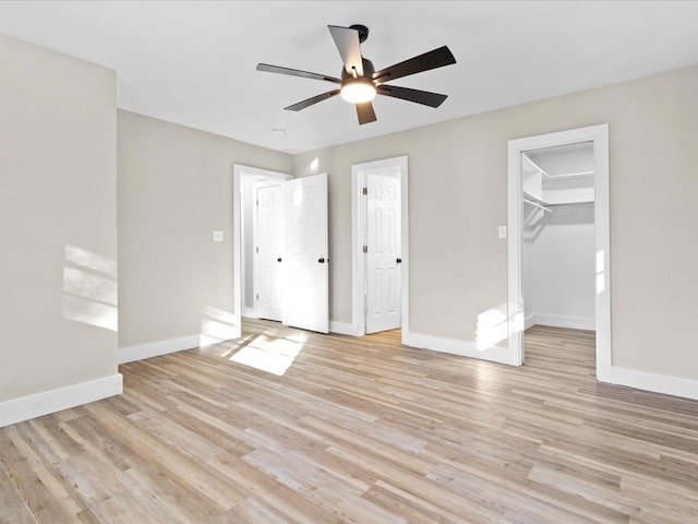 unfurnished bedroom with ceiling fan, light wood-type flooring, and a spacious closet