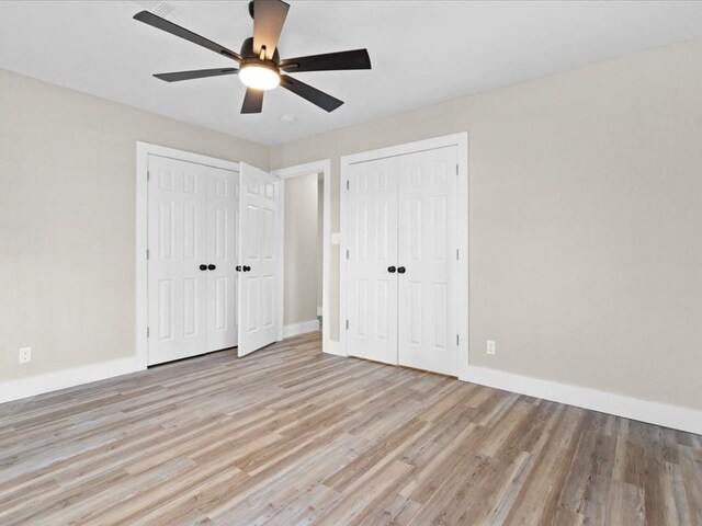 unfurnished bedroom featuring ceiling fan, two closets, and light hardwood / wood-style flooring